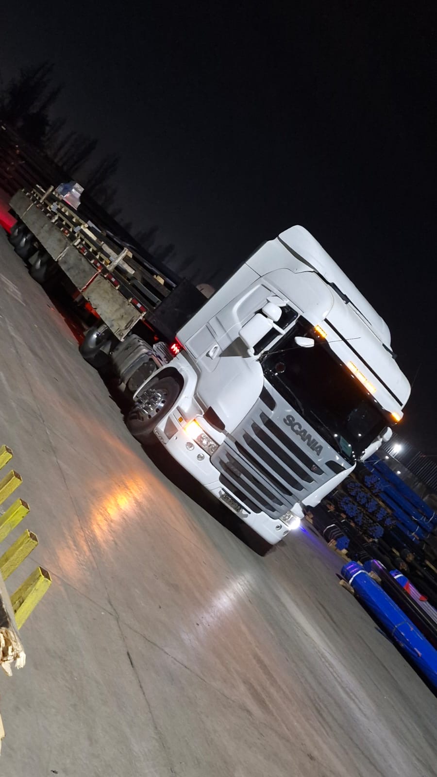 Tractocamión Scania blanco con carga sobre rampla